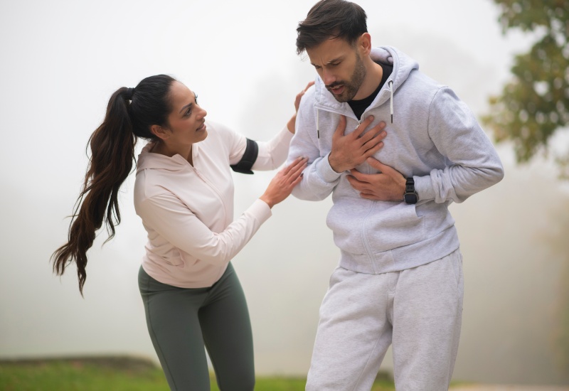 A man clutching his chest during a workout shows silent heart attack symptoms in Peoria, AZ