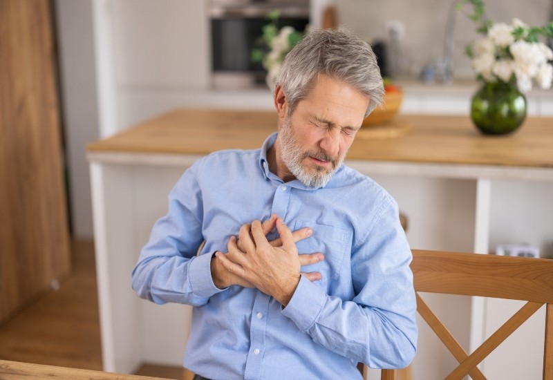 A man clutching his chest shows cardiac distress and needs care in Peoria, AZ