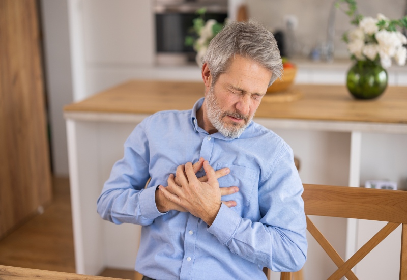 A man clutching his chest shows cardiac distress and needs care in Peoria, AZ