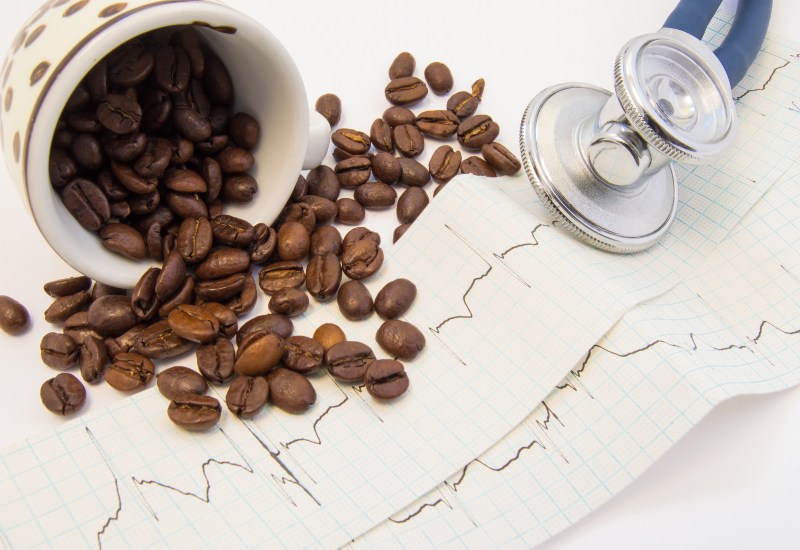 Coffee beans, an ECG strip, and stethoscope show caffeine's link to heart palpitations in Peoria, AZ